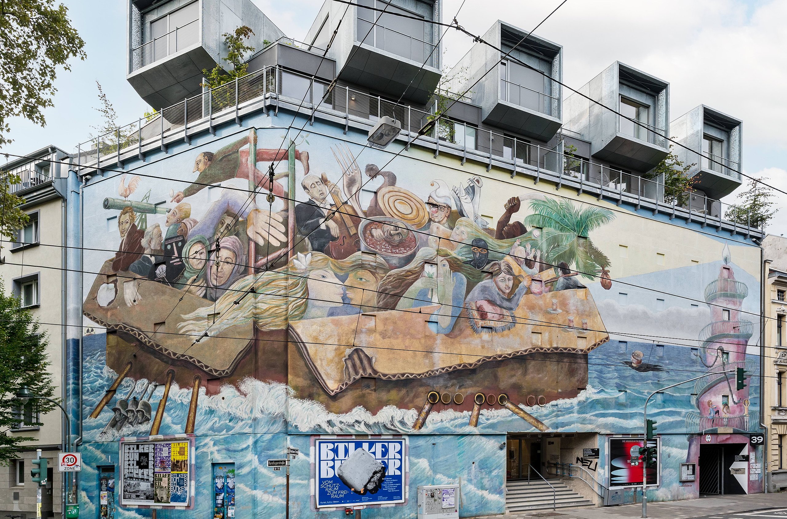 Große Wandmalerei auf der Fassade des Bilker Bunkers. Bild zeigt überfülltes Floß mit Menschen in stürmischer See.